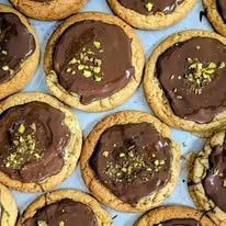 Cookies topped with chocolate and chopped pistachios